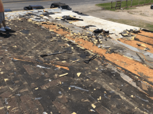 A house with visible wind and hail damage on its roof after a major storm